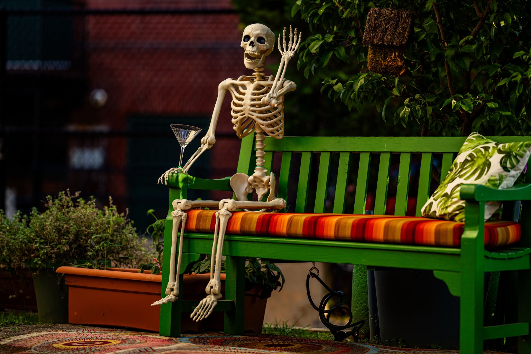 A decorative skeleton sitting on a bright green park bench, highlighting seasonal local festivals and events.