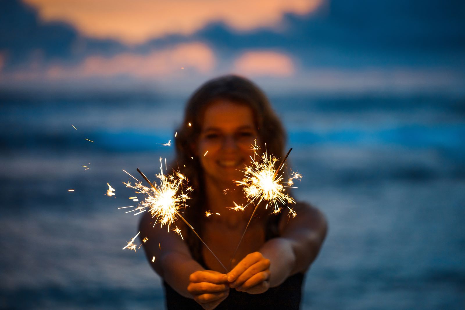 woman on beach holding sparklers