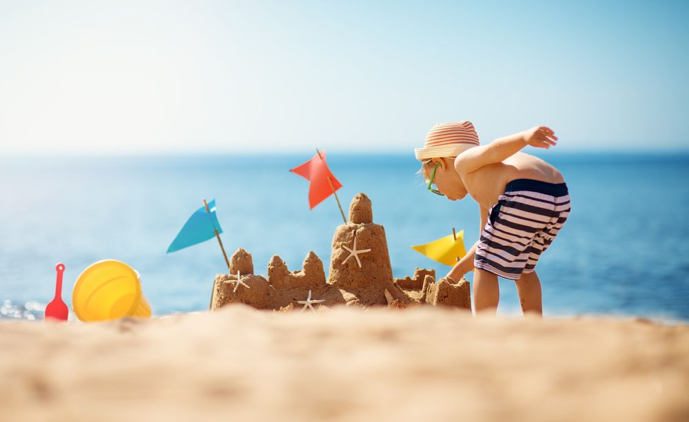 A close-up of a detailed sandcastle built on the soft beach sand with colorful flags, perfect for family-friendly vacations.