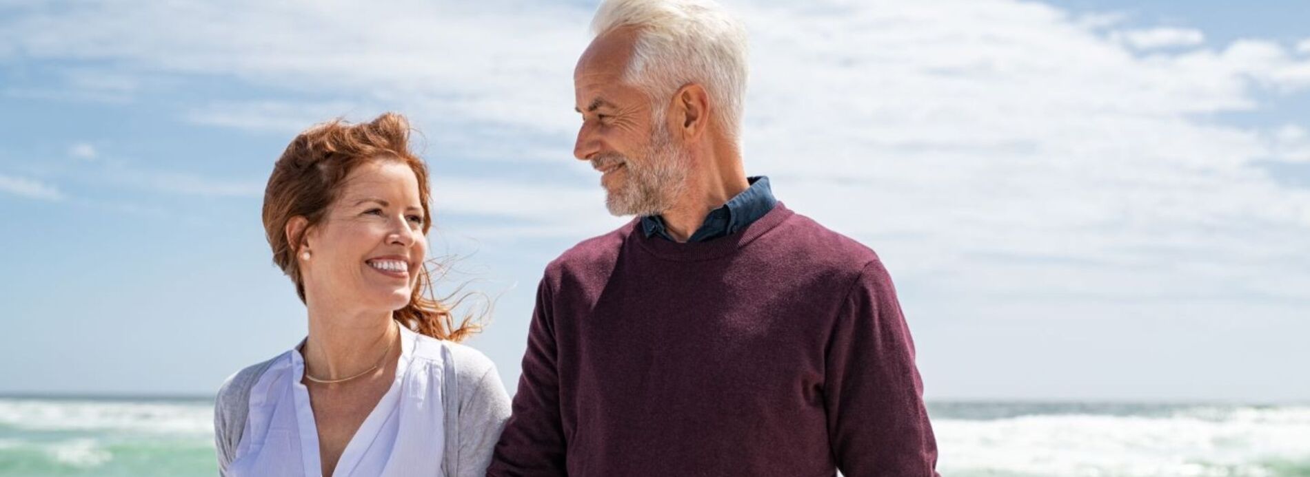 A happy mature gentleman smiling while enjoying an outdoor stroll near the coast on a pleasant afternoon.