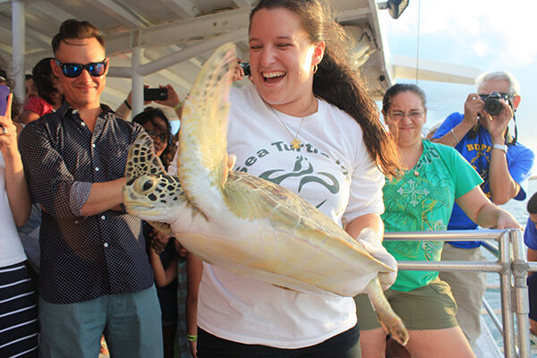 Sea-turtle-conservation-and-rescue-centers | South Padre Island Vacation Rentals Woman holding sea turtle in front of crowd