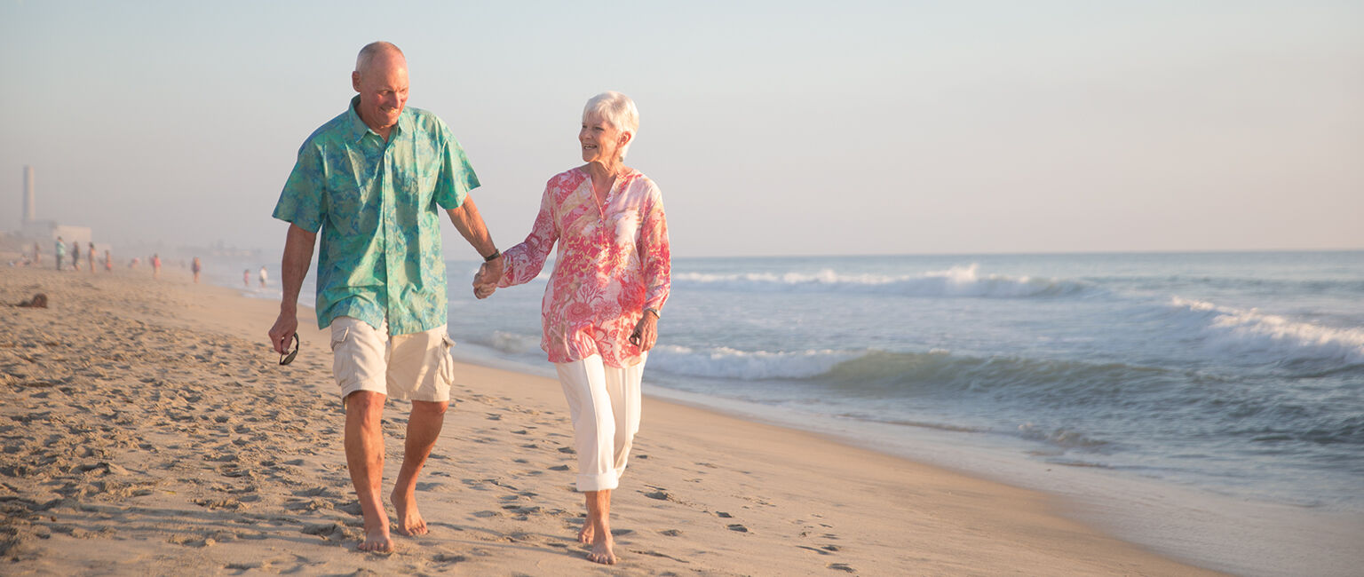 Multi-generational-family-walks-by-the-sea | South Padre Island Vacation Rentals older couple holds hands and walks on beach