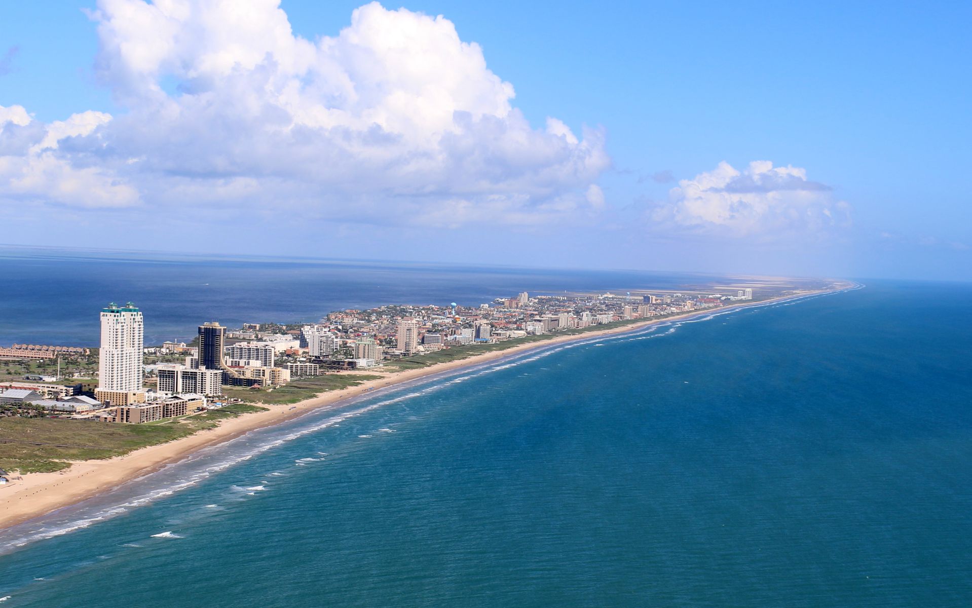 An aerial perspective looking down miles of pristine white sandy beaches meeting turquoise waters on the Gulf coast.