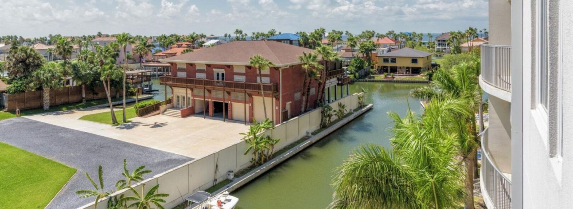 A scenic view looking down a deep-water canal bordered by luxury townhomes and private boating docks.