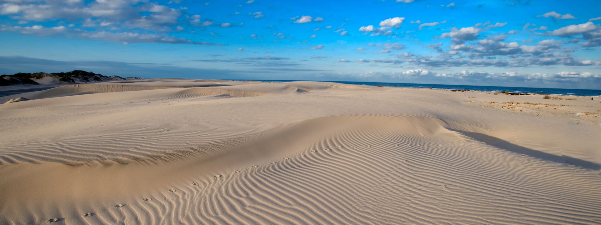 Rolling white sand dunes meeting the deep blue sky, showing the stunning natural landscapes surrounding your Padre Getaways beach rental.